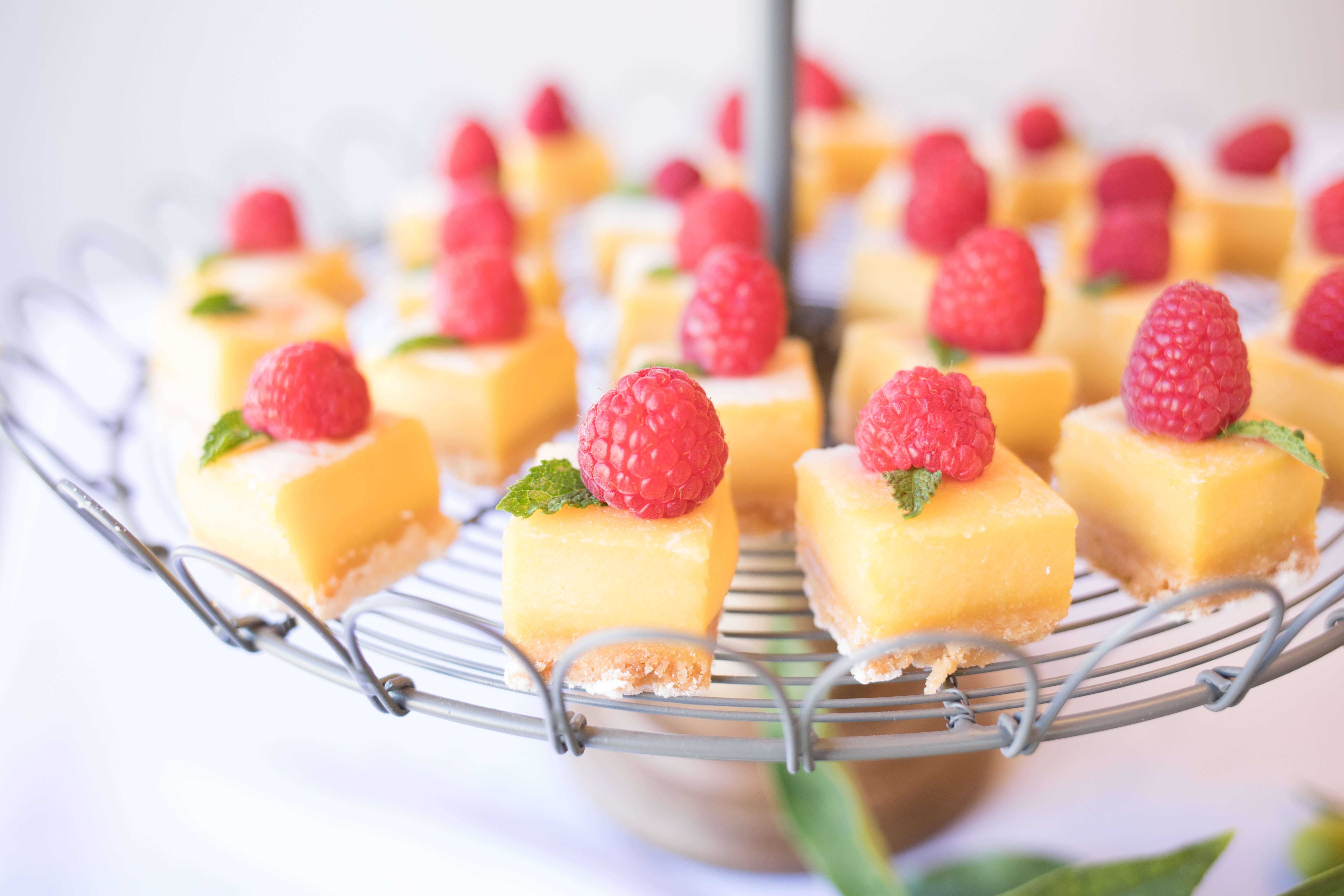 Bite sized lemon tarts each topped with a raspberry